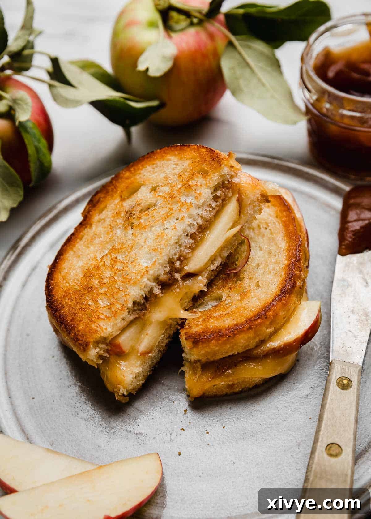 Crispy Apple Cheese Melt 2 A gray plate with an Apple Grilled Cheese Sandwich on sourdough bread with apple butter cut in half, on the plate.