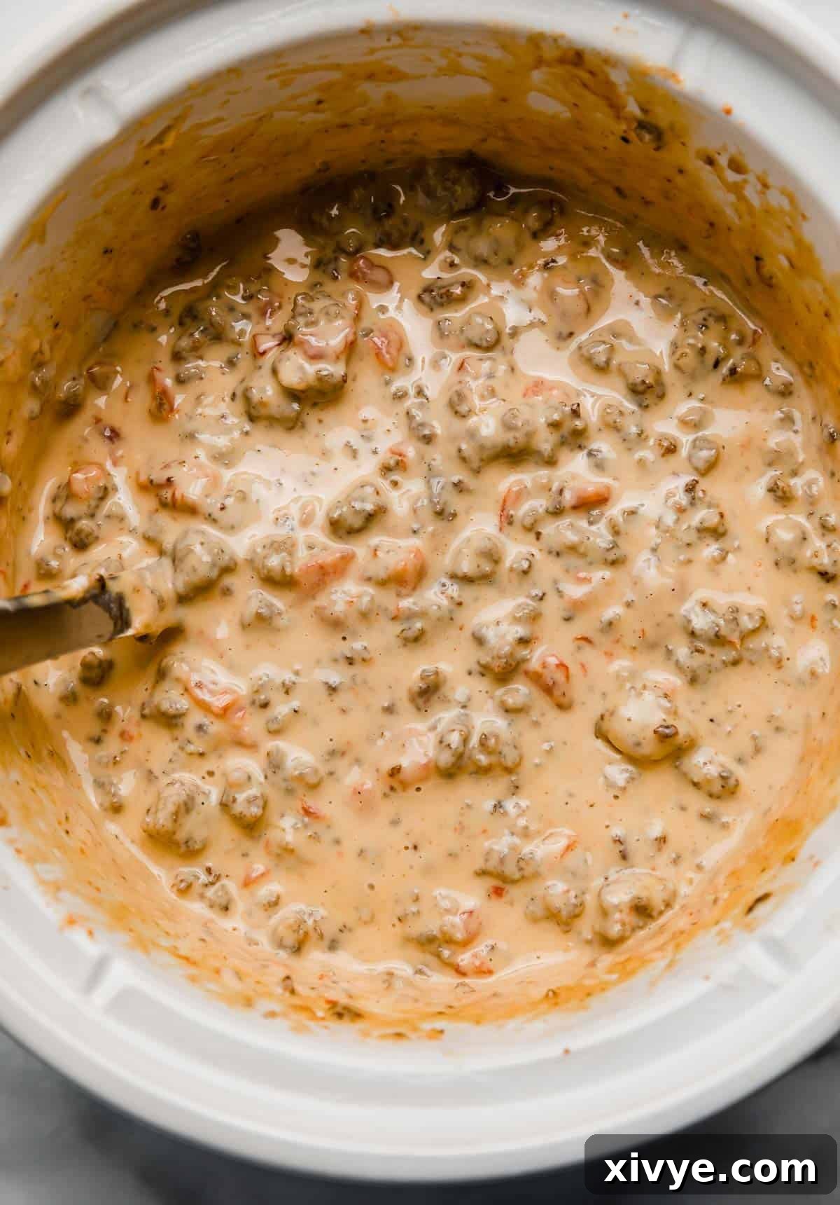 Kickin' Cream Cheese Sausage Dip 6 Overhead photo of Cream Cheese Sausage Rotel Dip in a white crock pot.