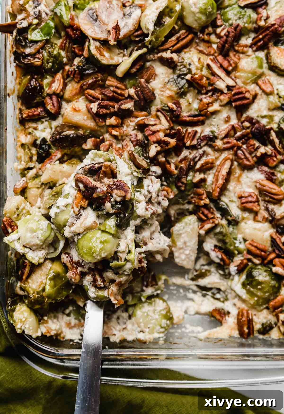 Brussels Sprouts Gratin with Bacon and gruyere topped with pecans in a baking dish.