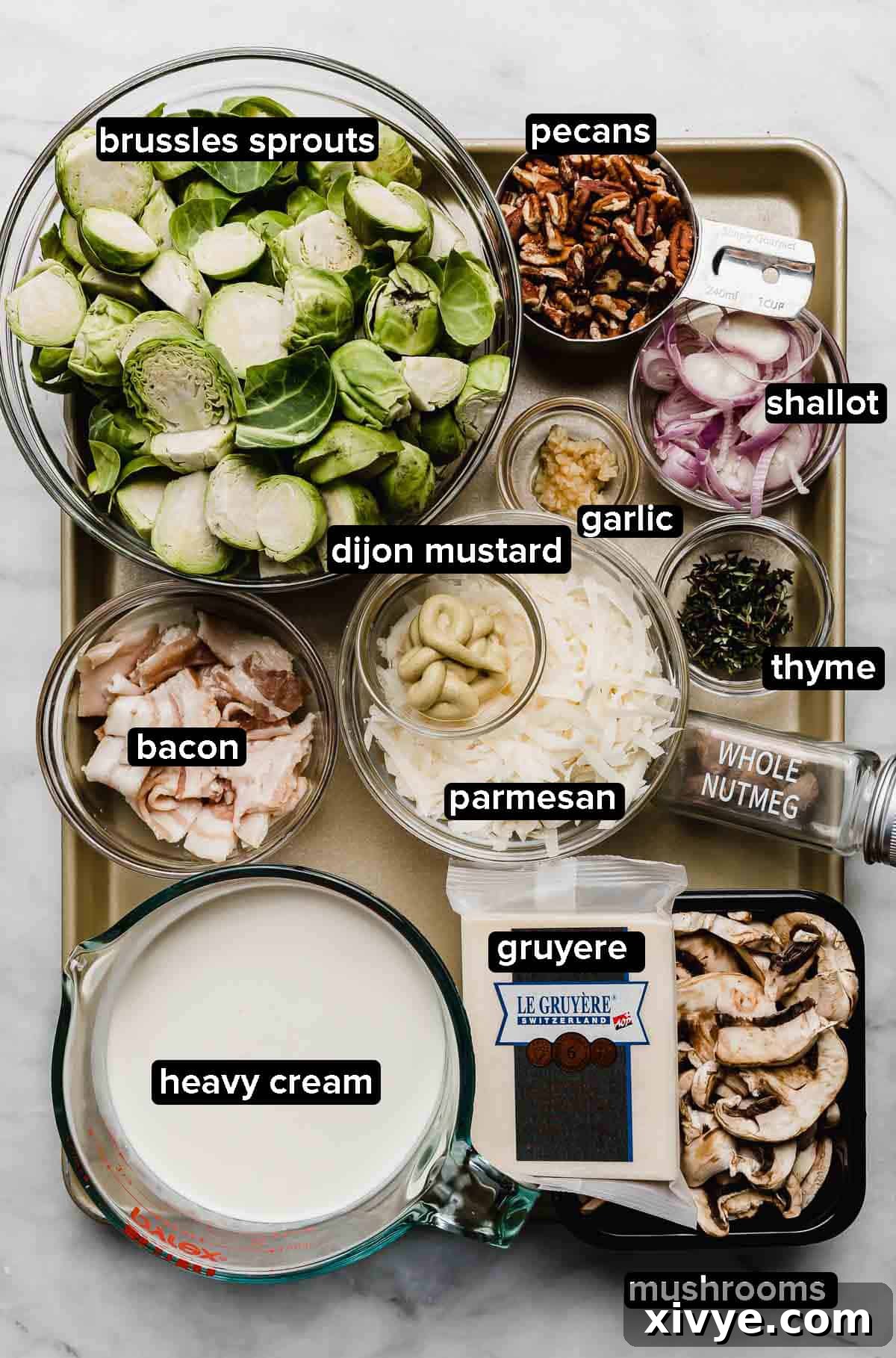 A gold baking sheet with Ingredients used to make a creamy Brussels sprouts gratin recipe with gruyere, bacon, pecans, mushrooms, and heavy cream.