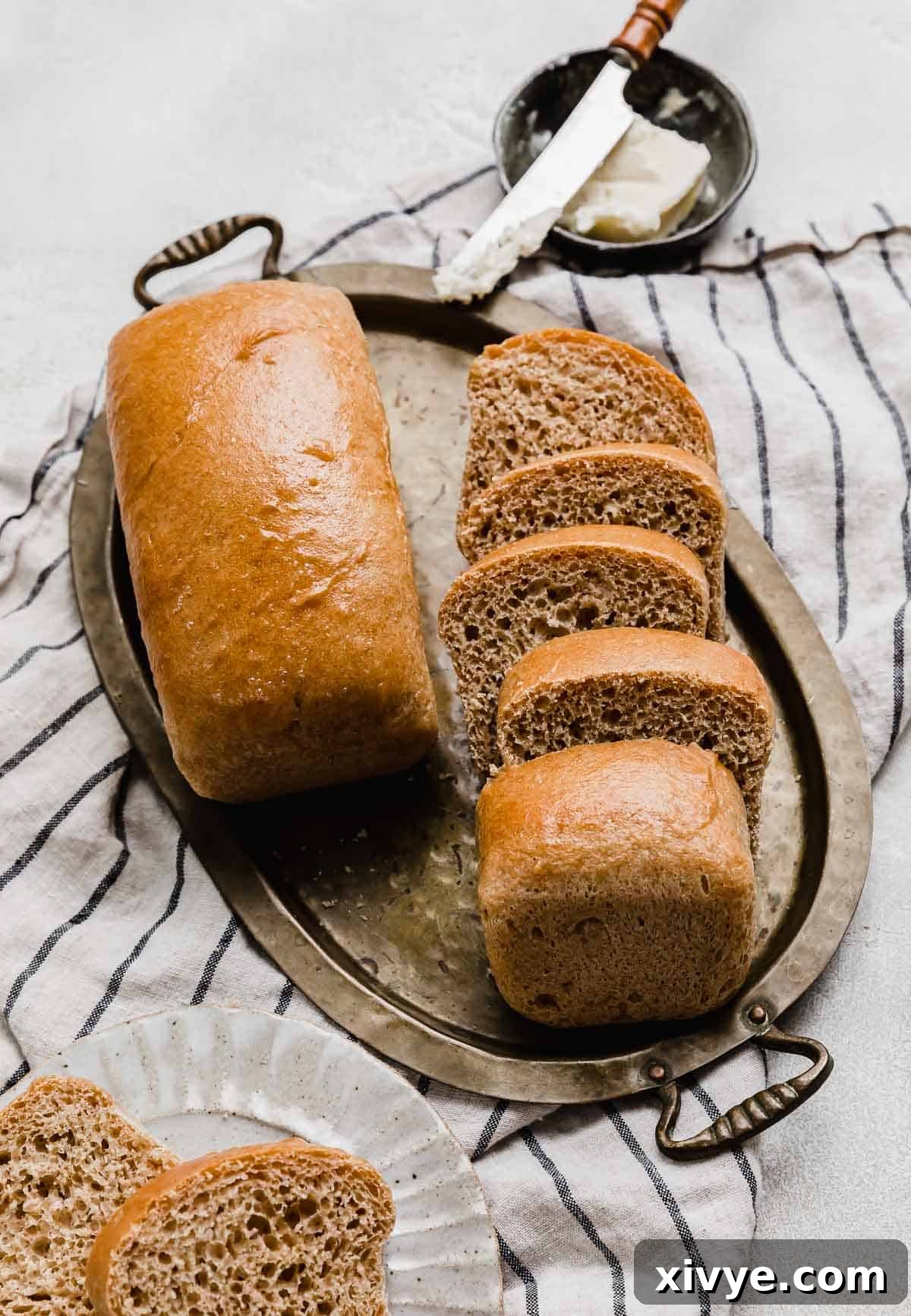 Fifty-Fifty White and Whole Wheat Bread 2 Two loaves of white and whole wheat bread (50/50 bread) one loaf sliced and the other loaf whole, on a gold tray.