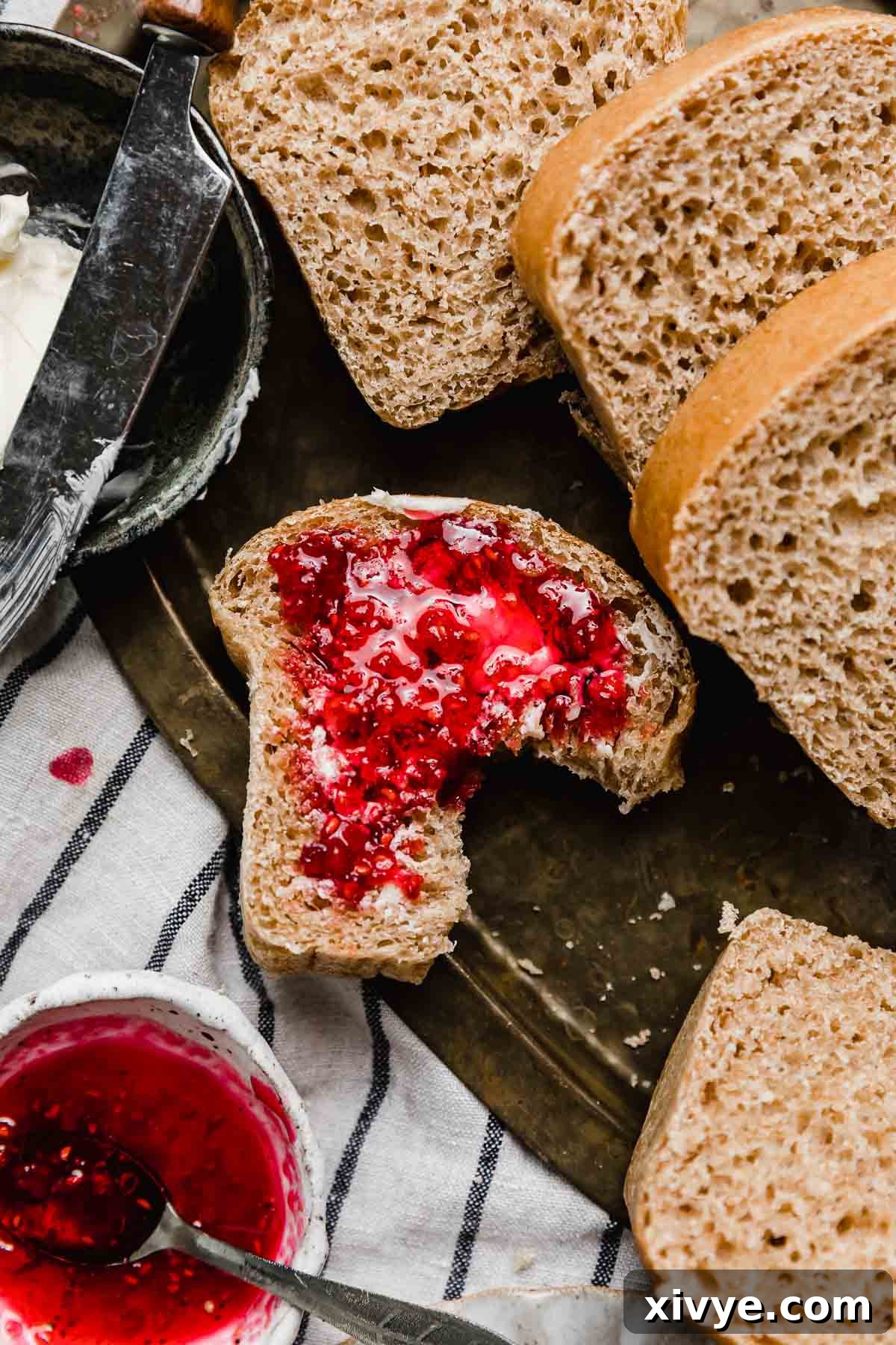 Fifty-Fifty White and Whole Wheat Bread 15 Raspberry jam topped slice of 50/50 bread with a bite taken out of the bread.
