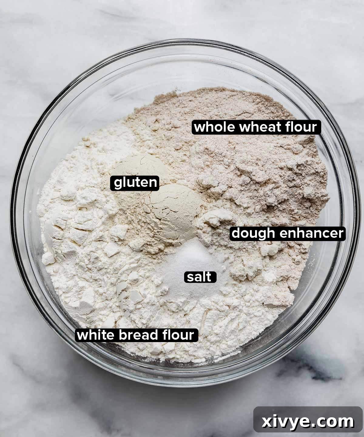 Fifty-Fifty White and Whole Wheat Bread 5 Glass bowl with dry ingredients used to make 50/50 Bread (White/Wheat Bread Recipe) including flour, dough enhancer, gluten, salt.