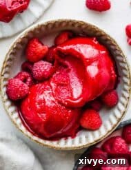 Crimson Raspberry Chill 8 A bowl filled with two scoops of Raspberry Sorbet, on a white background.