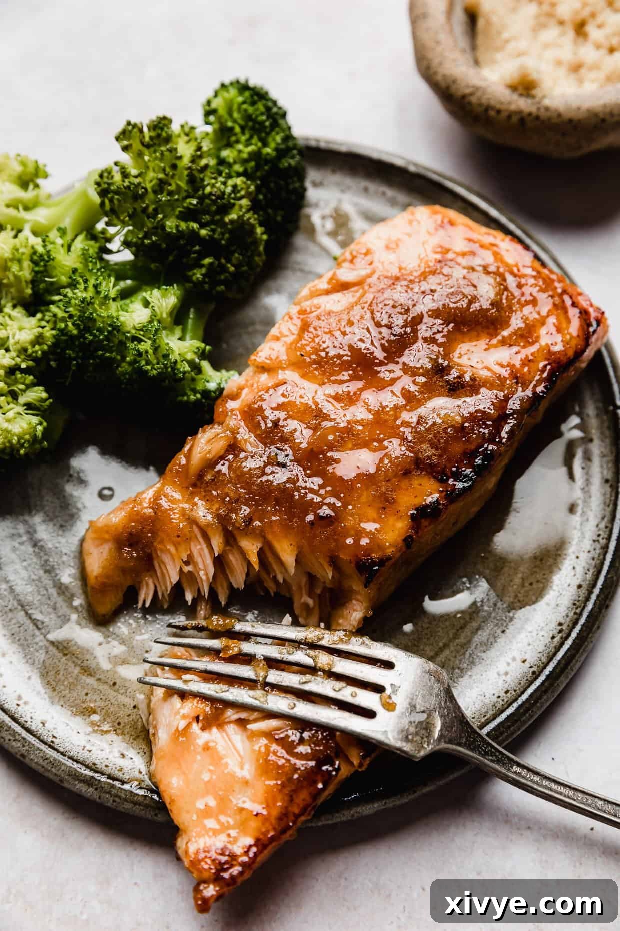 Brown Sugar glazed Salmon on a grey plate on a white background, garnished with fresh herbs.
