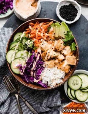 Effortless Bang Bang Chicken Bowls 12 Colorful Bang Bang Chicken Bowls with cooked rice, red cabbage, cucumbers, and carrots in a brown bowl.