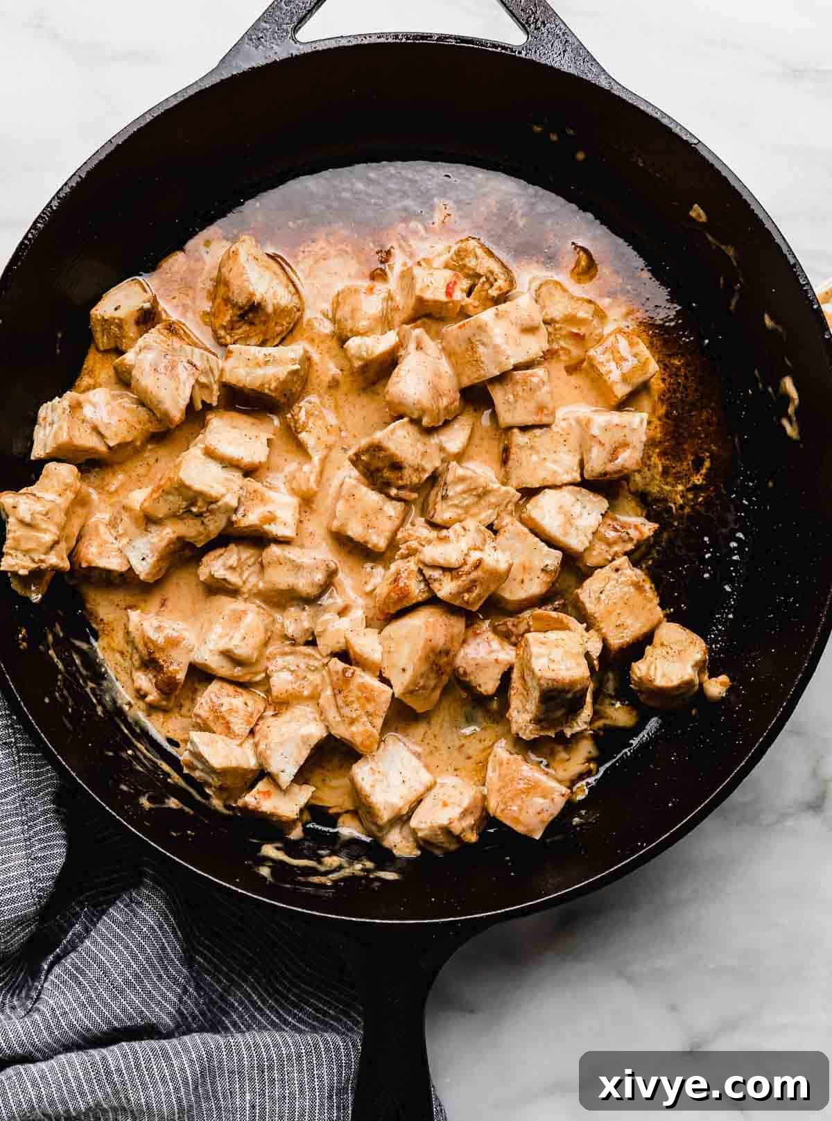 Effortless Bang Bang Chicken Bowls 8 Chopped and seasoned chicken breasts in a black skillet coated in homemade bang bang sauce.
