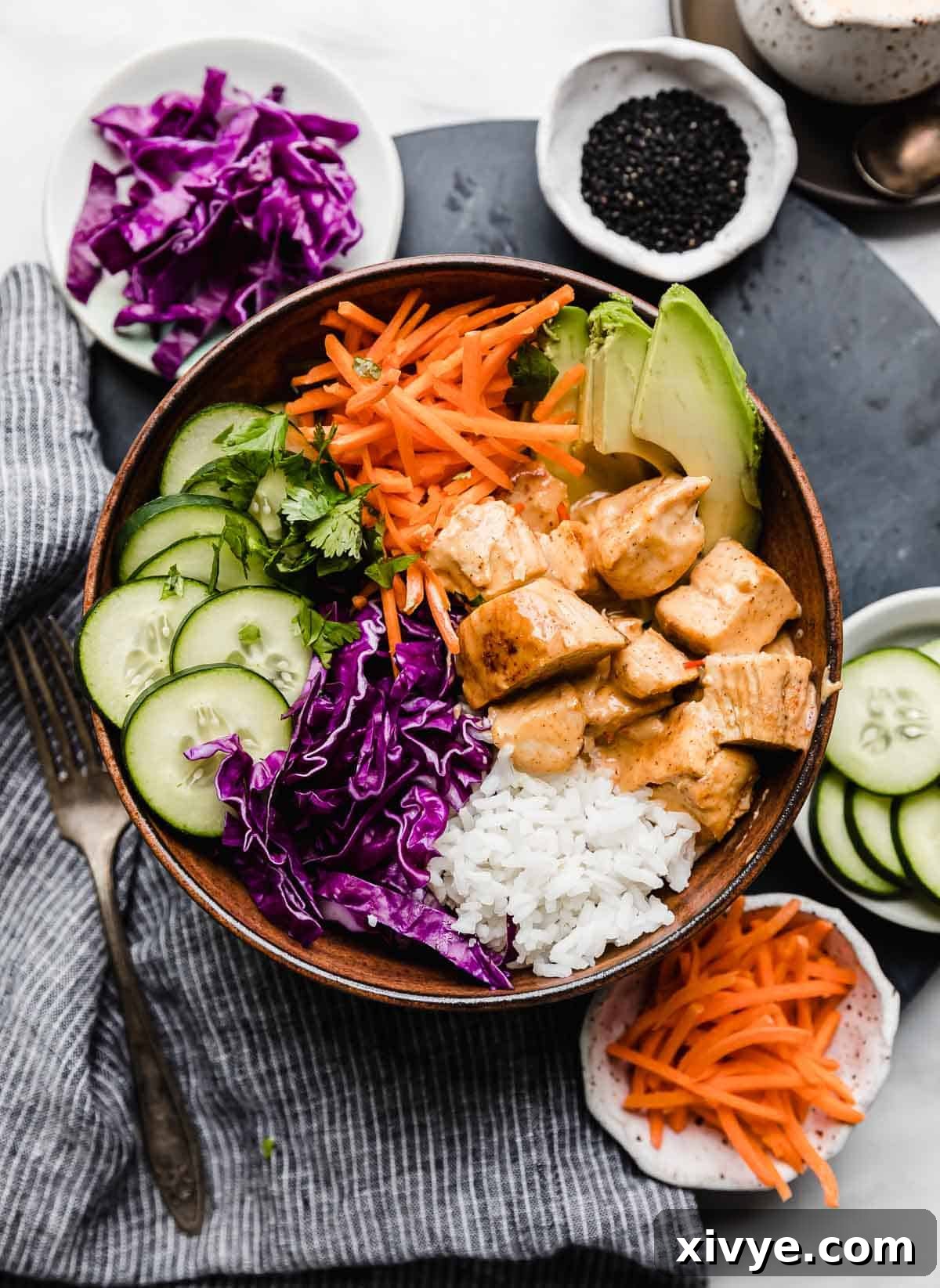 Effortless Bang Bang Chicken Bowls 9 Bang Bang Chicken Bowls with rice, red cabbage, cilantro, carrots and avocado.
