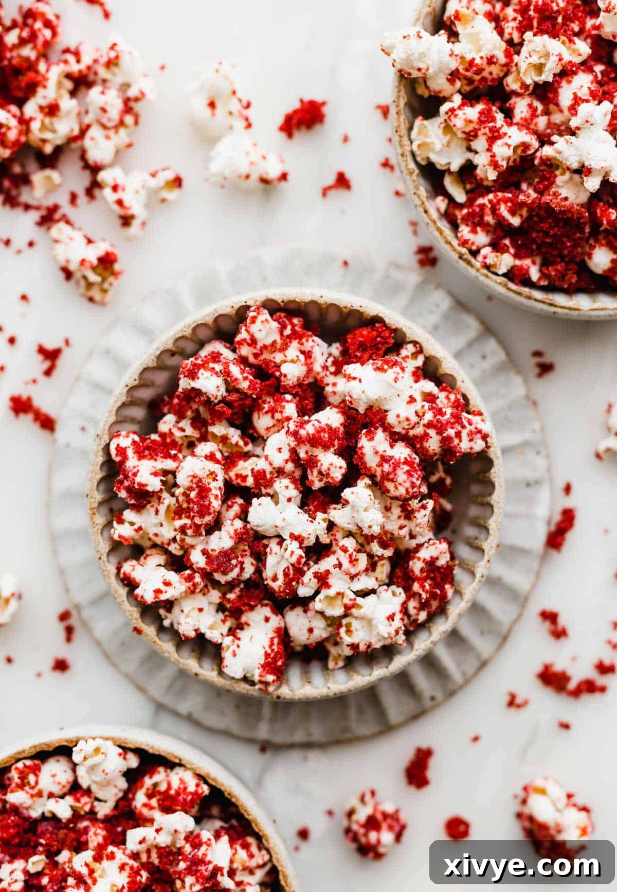 Red Velvet Popcorn in a bowl on a white background, showcasing its vibrant red crumbs and white chocolate coating.