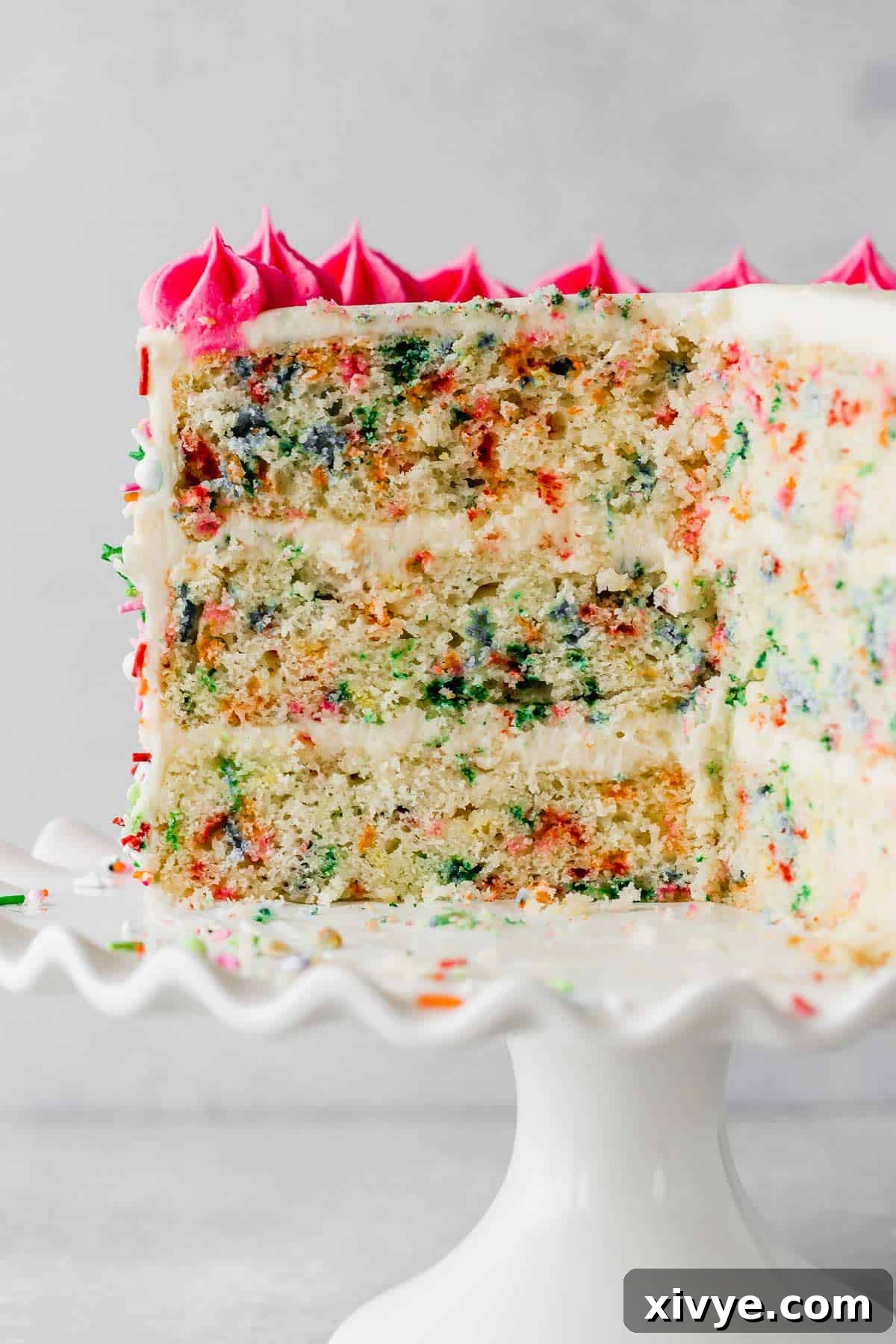 A stunning three-layer homemade funfetti cake presented on a white cake stand, showcasing its festive appearance.