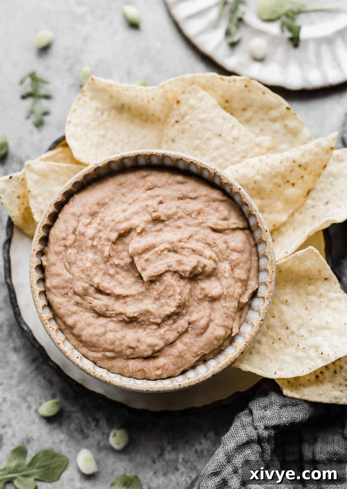 Hands-Off Slow Cooker Refried Beans 2 Overhead photo of Slow Cooker Refried Beans in a tan colored bowl with tortilla chips surrounding the beans.