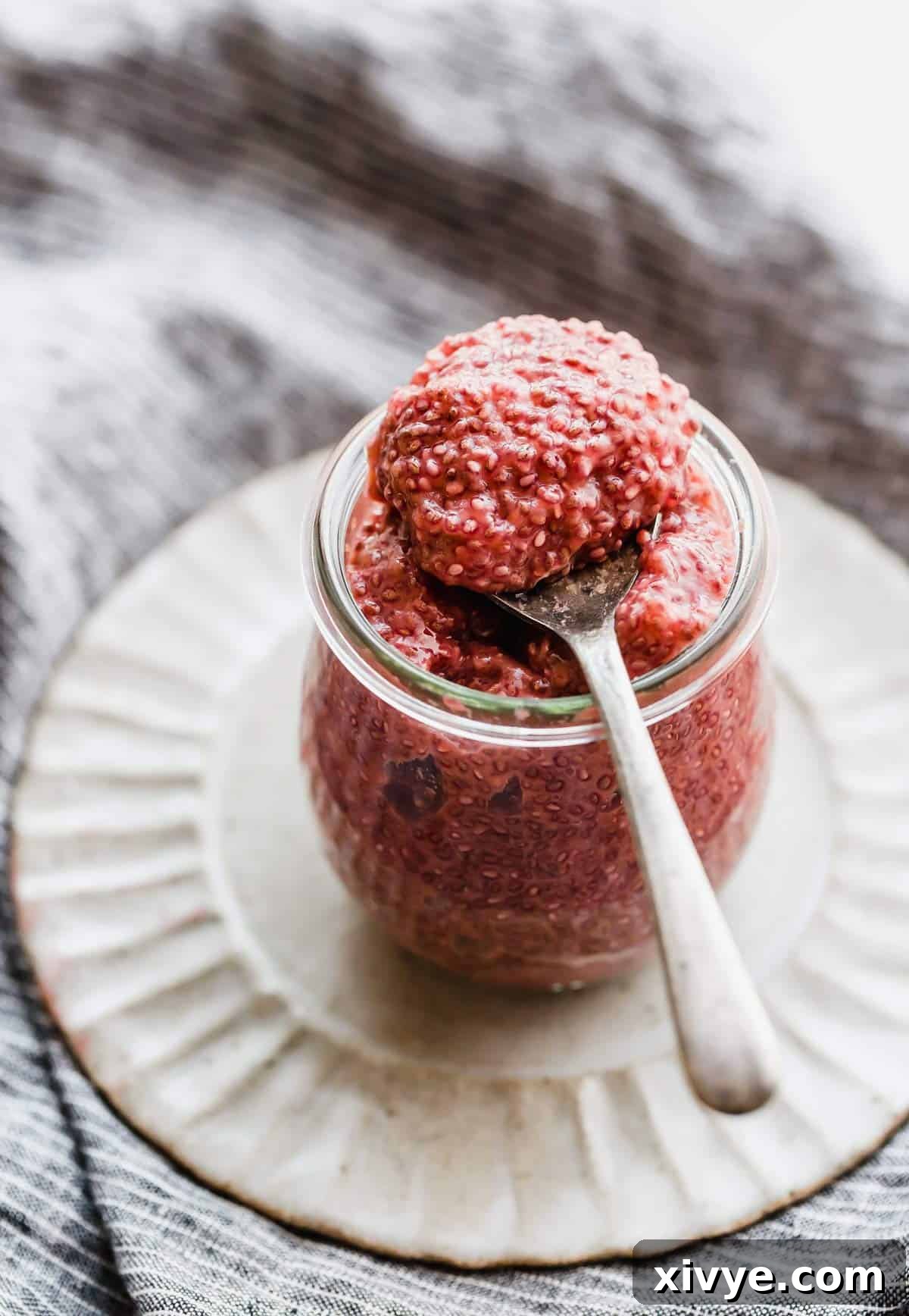 Vibrant Blood Orange Chia Delight 2 A spoon scooping out Blood Orange Chia Pudding from a glass jar, showcasing its beautiful pink color and creamy texture.