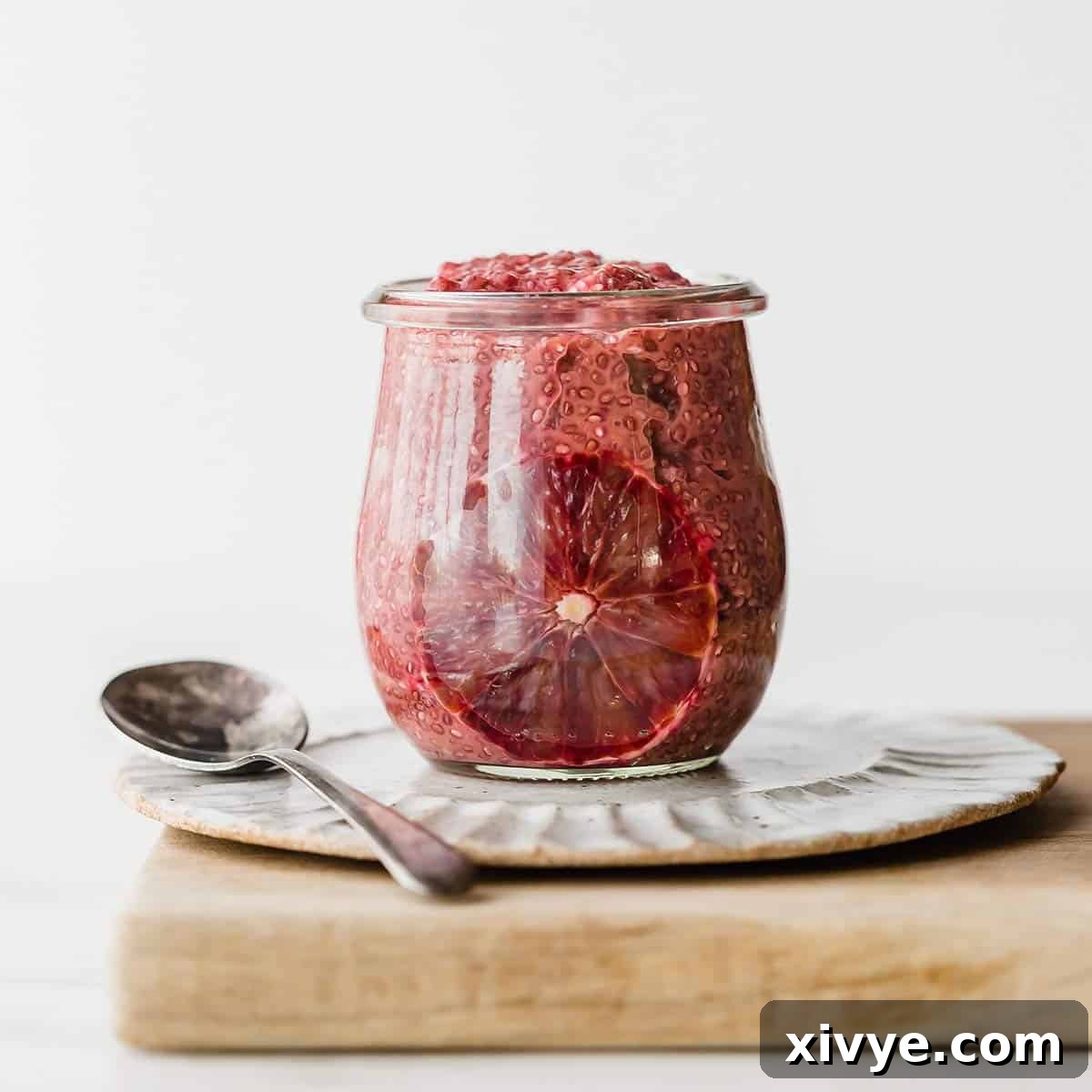 Vibrant Blood Orange Chia Delight 4 A glass jar filled with vibrant Blood Orange Chia Pudding, elegantly presented against a clean white background.