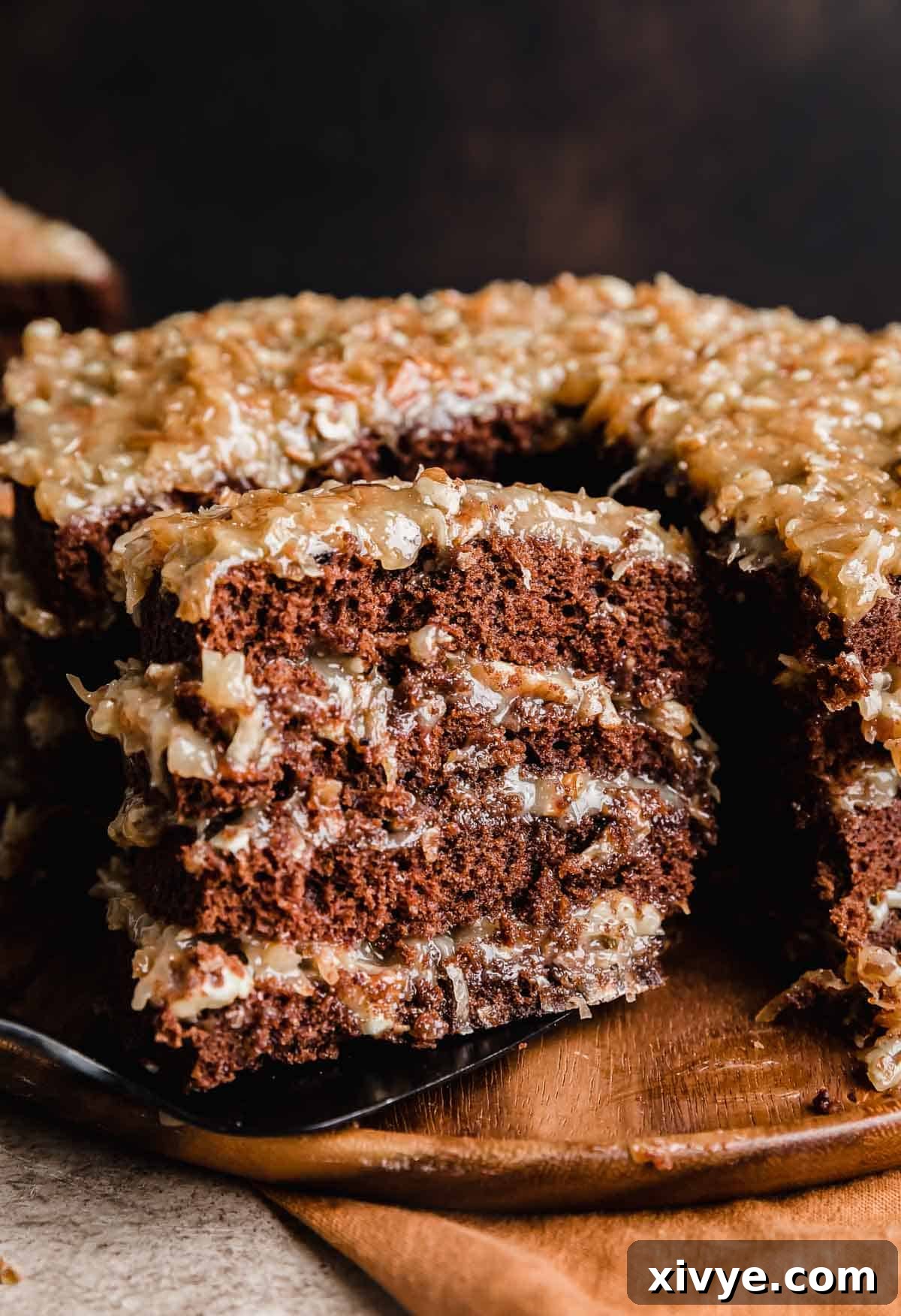 A slice of a four layer Traditional German Chocolate Cake balancing on a spatula, ready to be served.