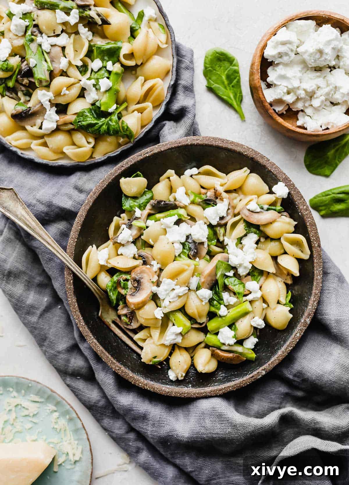 Asparagus Spinach Pasta in a black bowl, with goat cheese over the pasta.