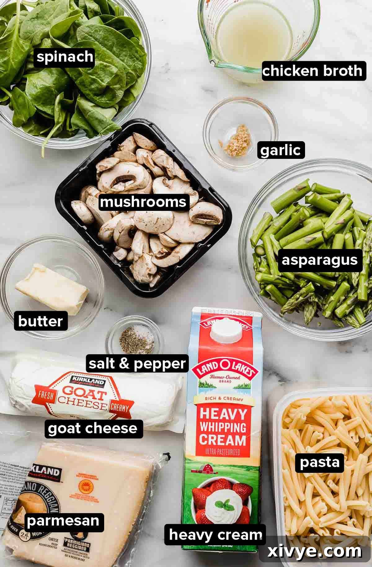 Asparagus Spinach Pasta ingredients on a marble background: spinach, pasta, asparagus, garlic, parmesan, goat cheese, heavy cream, mushrooms.