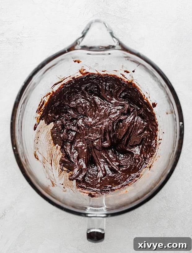 A glass bowl filled with rich brownie cookie batter, perfectly mixed and ready for scooping.