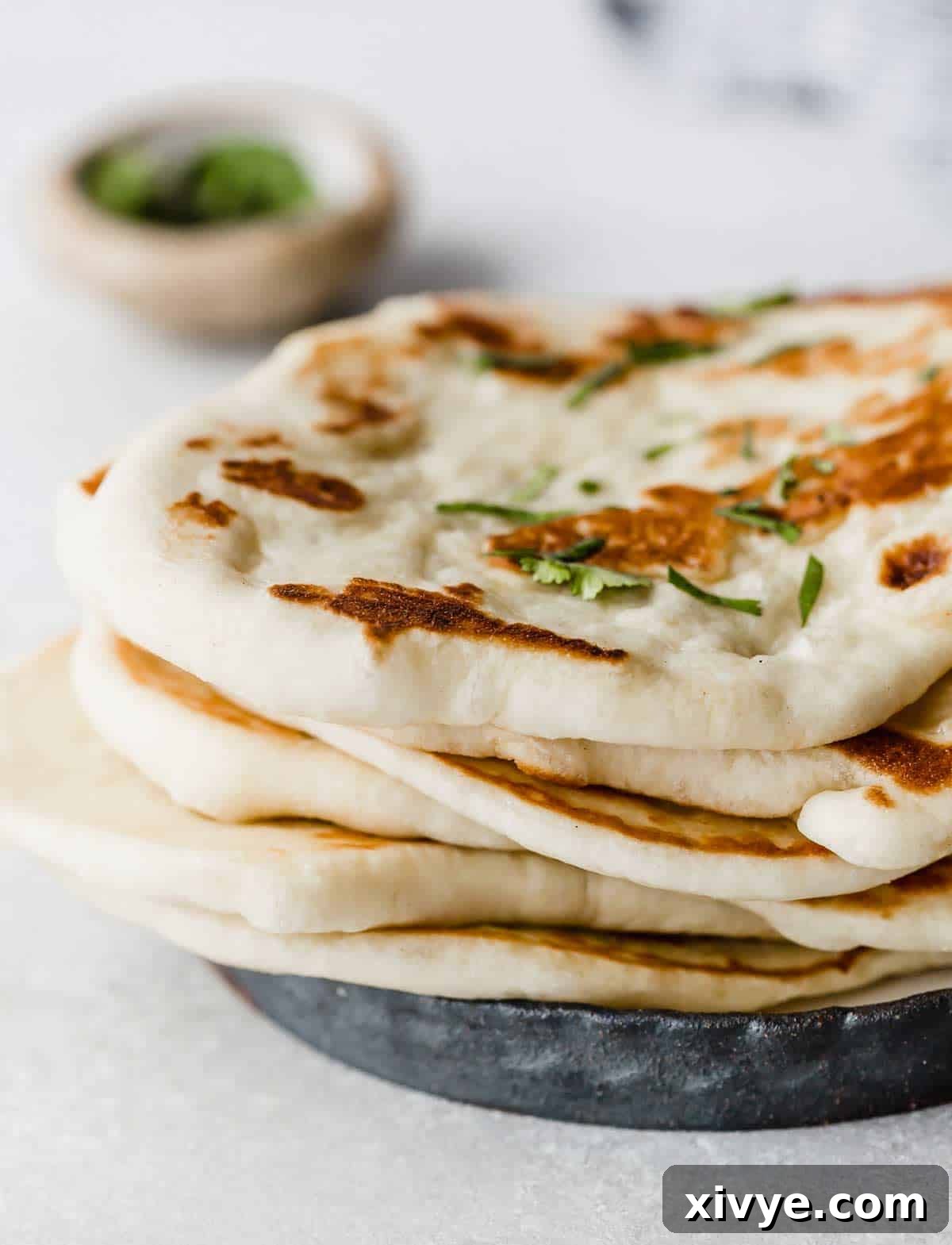 A stack of Greek Yogurt Naan Bread on a black plate.