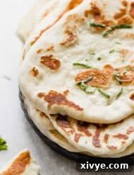 Golden brown cooked Yogurt Naan Bread on a black plate.