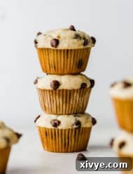 Three golden-brown buttermilk banana chocolate chip muffins stacked against a white background.