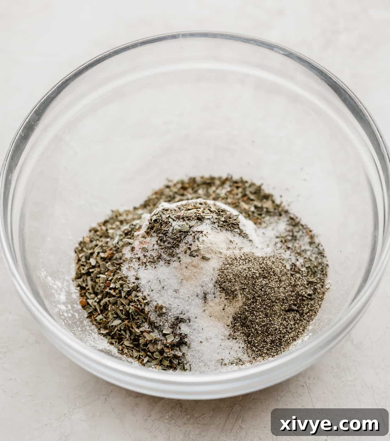 Crispy Baked Chicken Drumsticks 4 A glass bowl filled with a perfectly mixed blend of flour, cornstarch, paprika, garlic powder, basil, thyme, and oregano, ready for coating chicken.