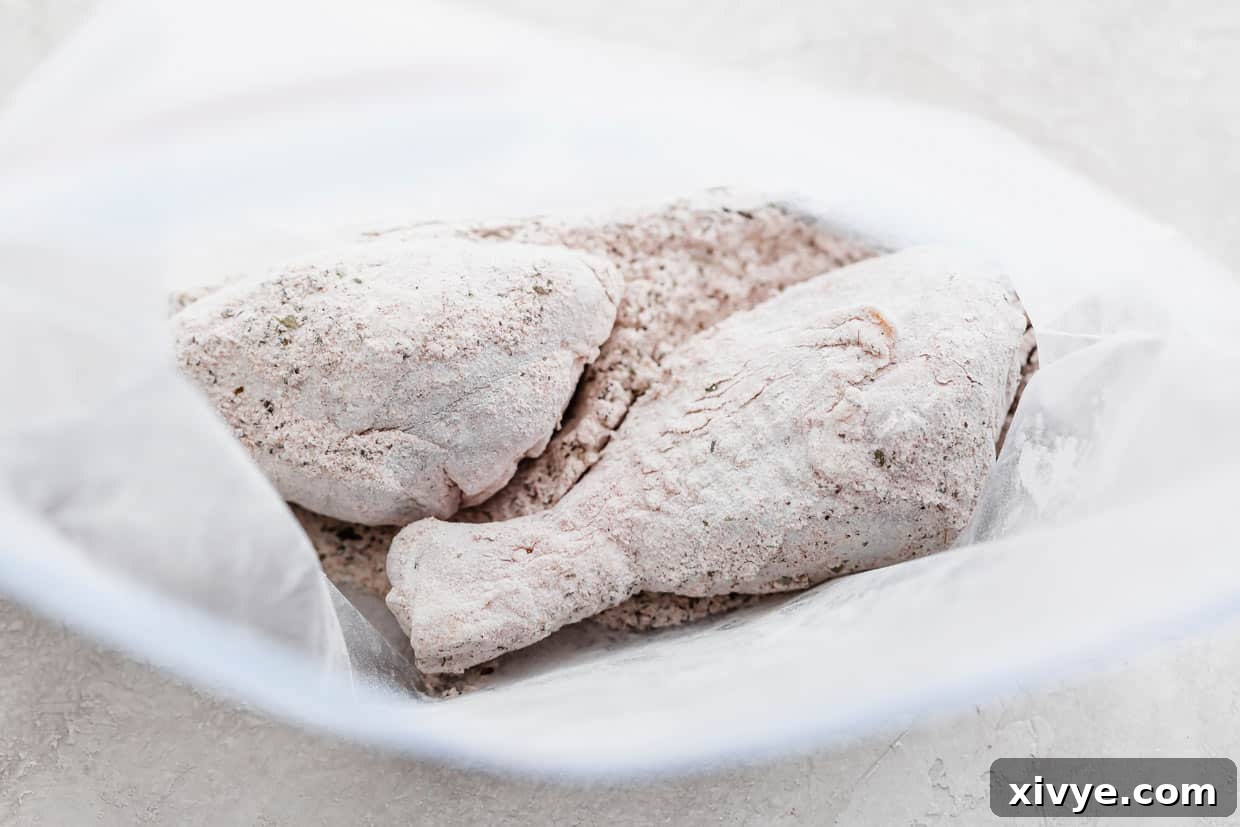Crispy Baked Chicken Drumsticks 6 Two chicken legs thoroughly coated in flour and cornstarch seasoning, visible inside a sealed ziplock bag.