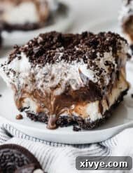 A slice of Oreo Ice Cream Cake on a white plate topped with crushed Oreos.