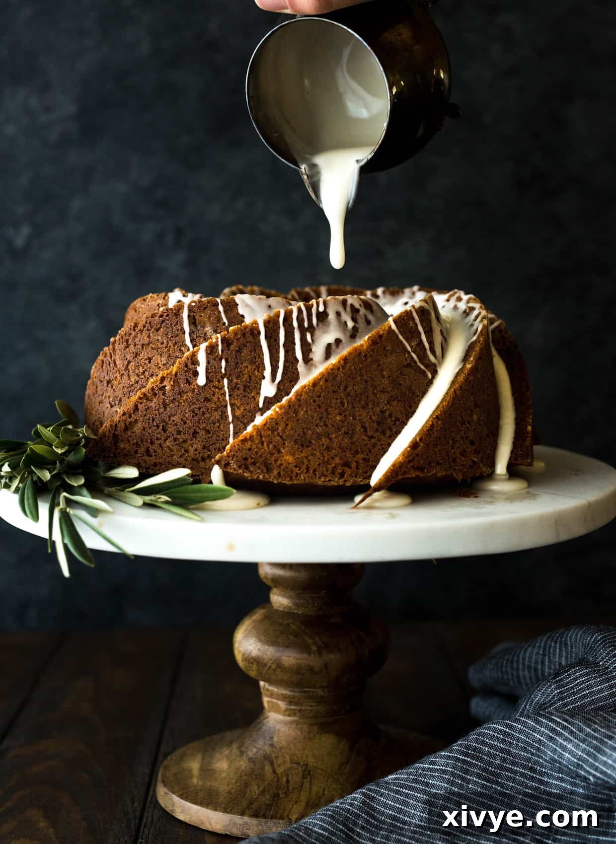 Gingerbread bundt cake sitting on a cake stand, with maple glaze slowly drizzling over the cake, creating an appealing visual.