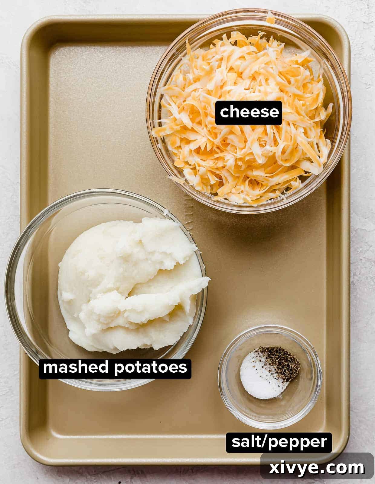 Homemade Pierogie filling ingredients: cheese, mashed potatoes, salt and pepper, on a bronze baking sheet.