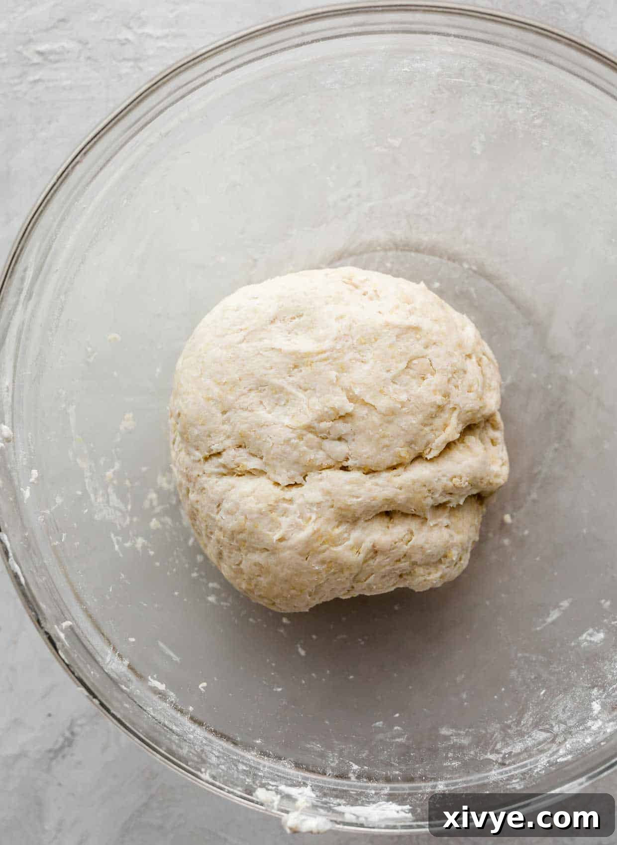 Pierogie dough with sour cream, in a ball in a glass bowl.