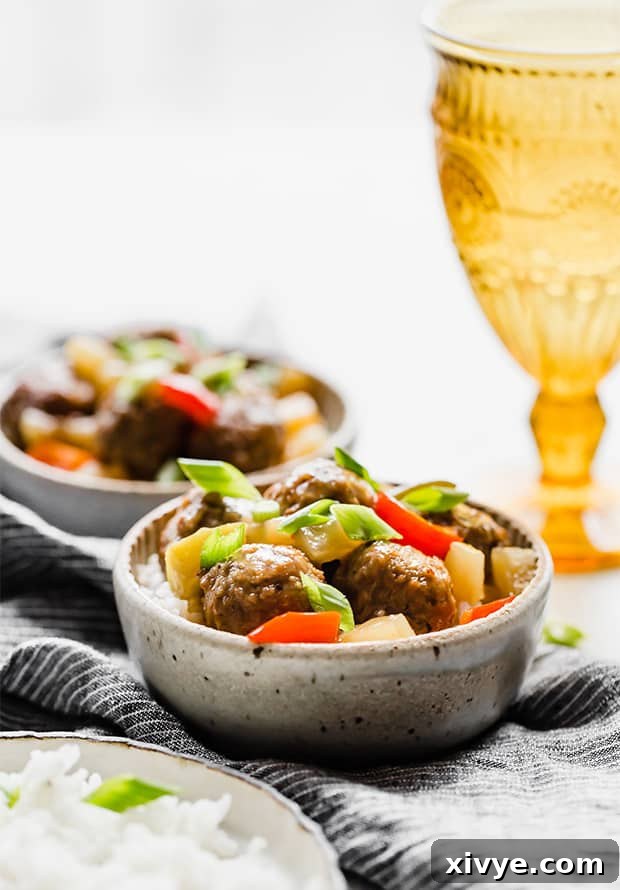 Delectable Sweet and Sour Slow Cooker Meatballs 3 Two bowls of Sweet and Sour Meatballs served over a bed of fluffy white rice, with a yellow cup in the distance, showcasing a complete meal.
