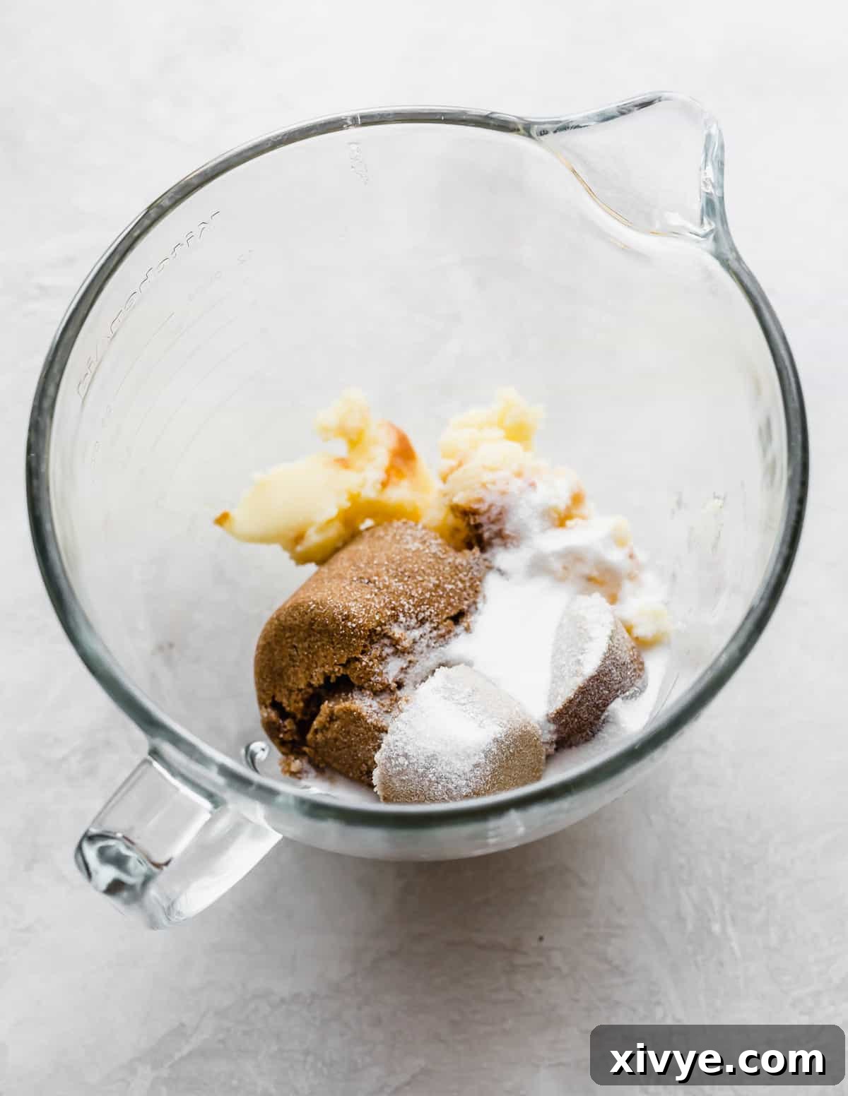 Caramelized Butter Chocolate Chip Cookies 6 Sugar, dark brown sugar, and solidified brown butter combined in a clear glass stand mixer bowl, ready for creaming.
