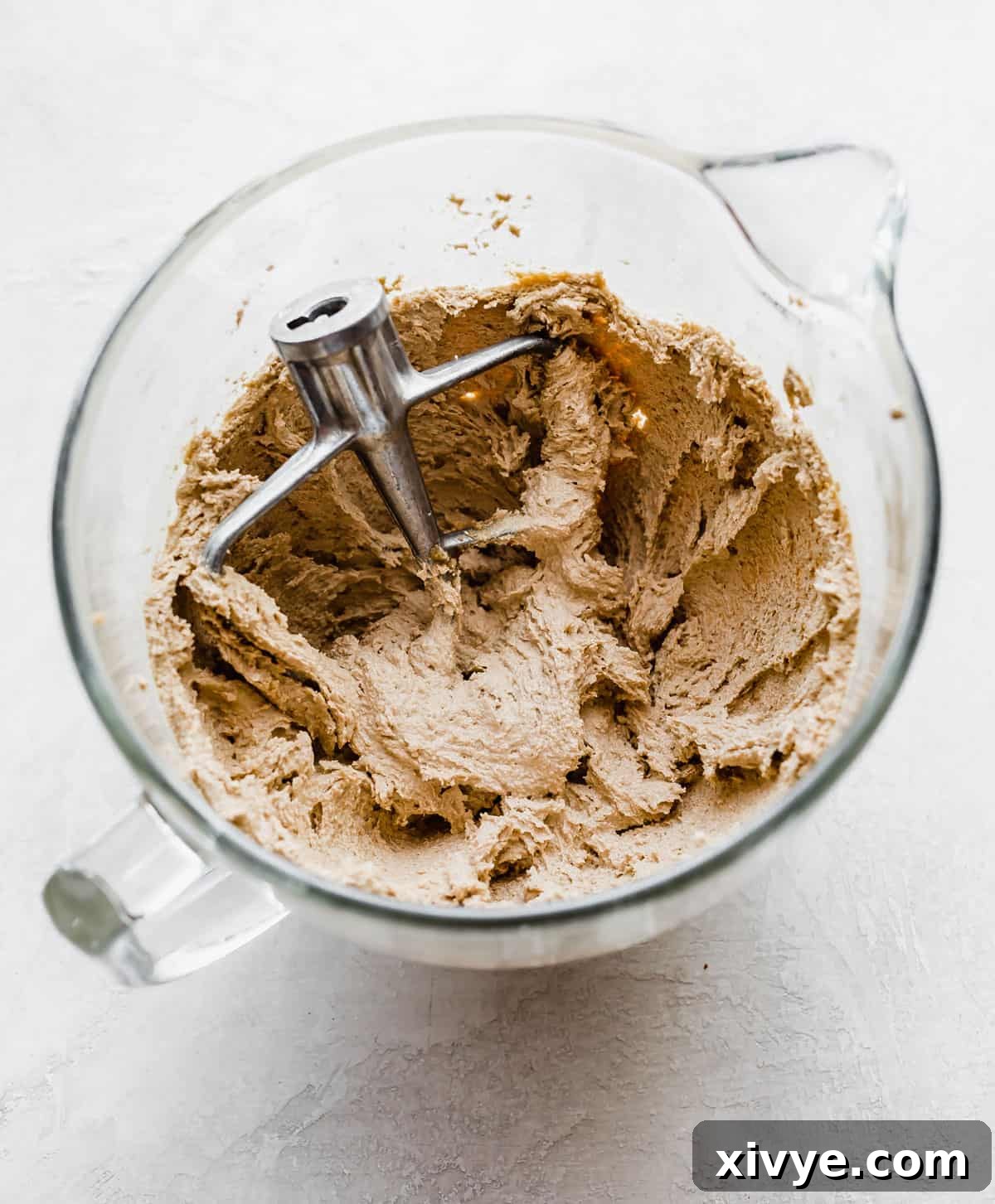 Caramelized Butter Chocolate Chip Cookies 7 Creamed brown butter and sugars in a glass bowl on a pristine white background, showcasing the fluffy texture for making Brown Butter Chocolate Chip Cookies with oat flour.