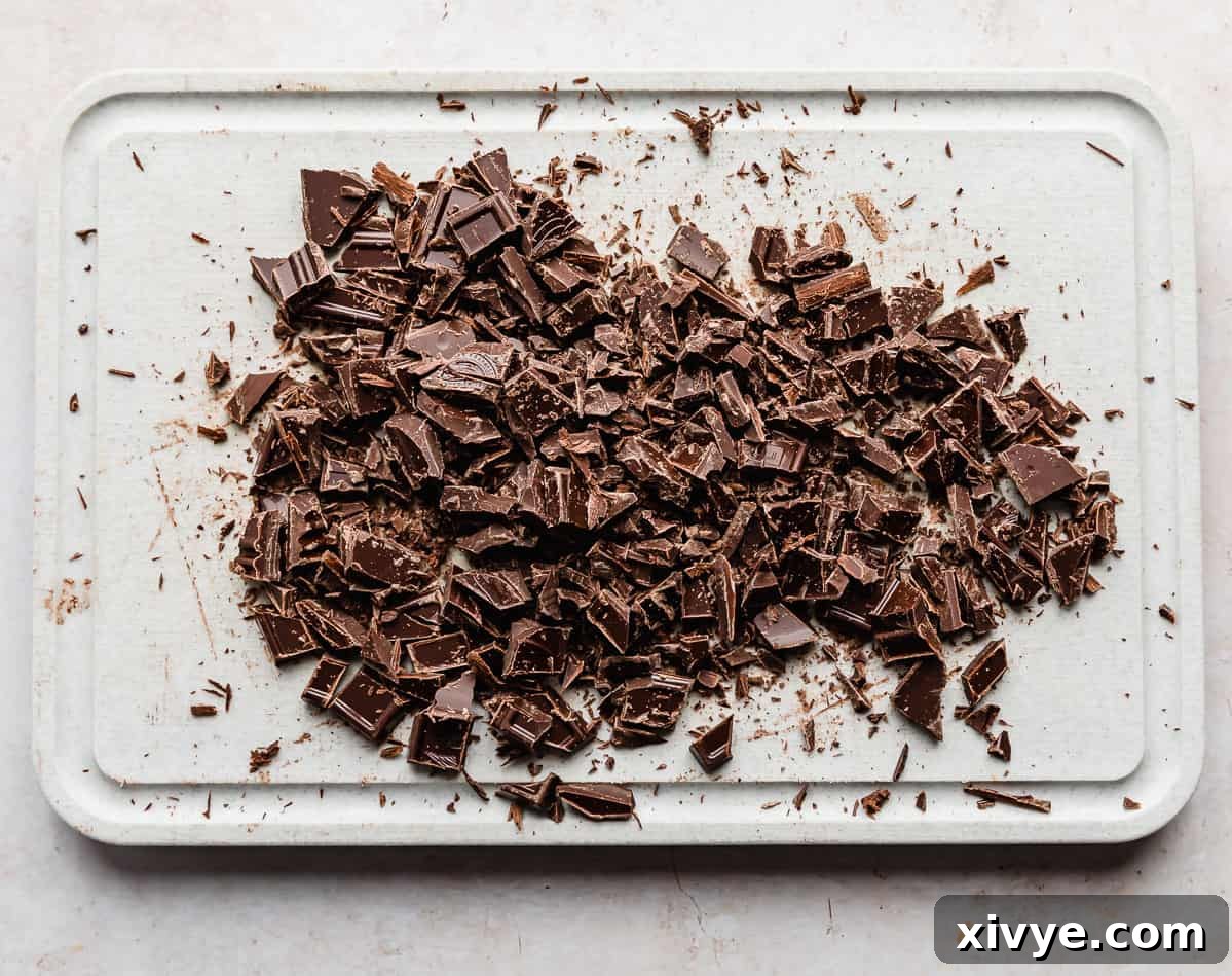 Decadent Chocolate Buttercream 4 Finely chopped semi-sweet chocolate on a gray cutting board, ready for melting.