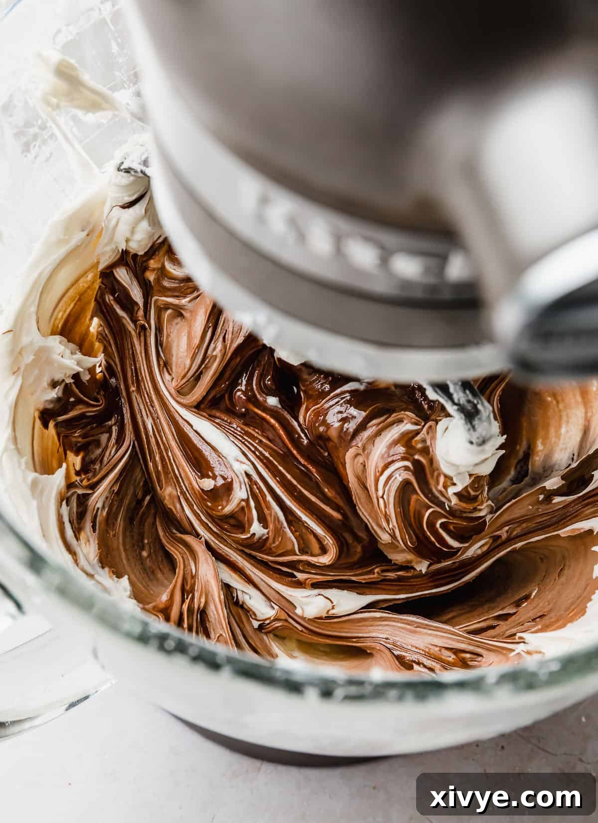 Decadent Chocolate Buttercream 9 Rich, glossy Chocolate Buttercream Frosting with Melted Chocolate, perfectly whipped in a glass stand mixer bowl.