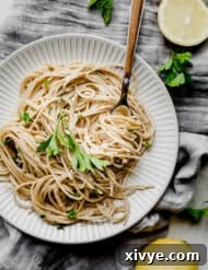 A white plate with a helping of lemon pasta on it, garnished with fresh parsley.