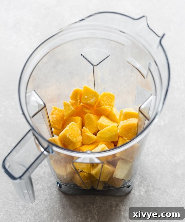 Sunshine Mango Pineapple Frosts 4 A blender jar filled with bright yellow frozen mango chunks, ready to be blended with pineapple juice.
