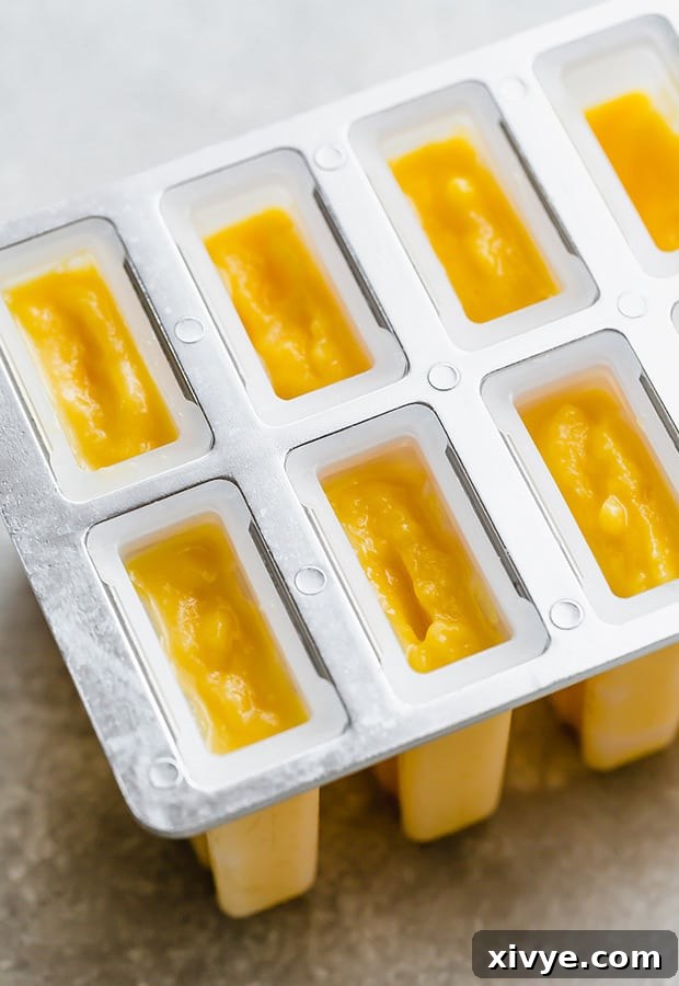 Sunshine Mango Pineapple Frosts 7 A set of filled popsicle molds with sticks inserted, neatly arranged and ready for the freezer.