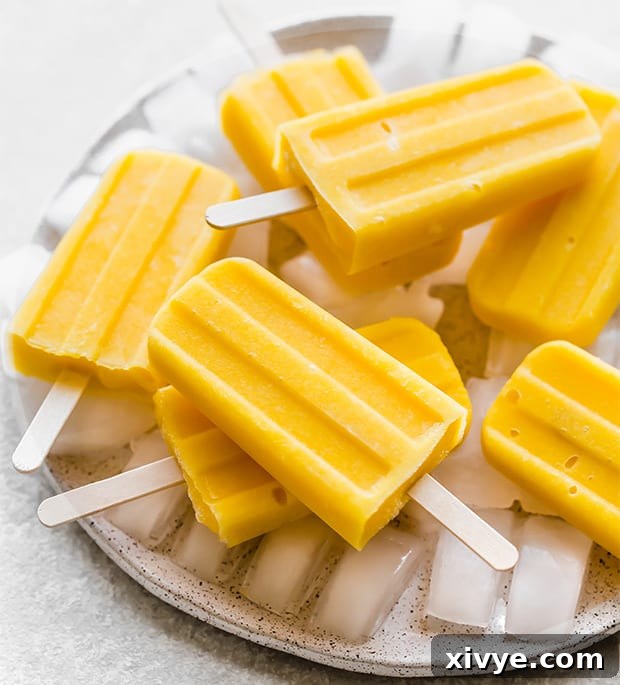 Sunshine Mango Pineapple Frosts 8 A beautifully composed shot of pineapple mango popsicles lying on a bed of ice, emphasizing their refreshing and icy nature.