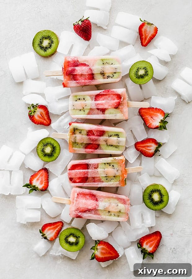 Five kiwi strawberry popsicles neatly arranged on top of a pile of ice cubes, showcasing their vibrant colors and frosty appeal.