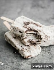 Decadent Cookies and Cream Pops 8 Three cookies and cream popsicles on top of each other, with a bite taken out of the top popsicle.