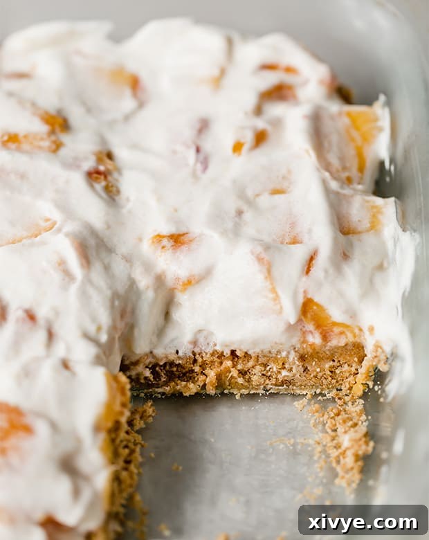 Sun-Kissed Peach Indulgence 7 A neatly cut square of peach dessert in a baking dish, showing distinct layers.