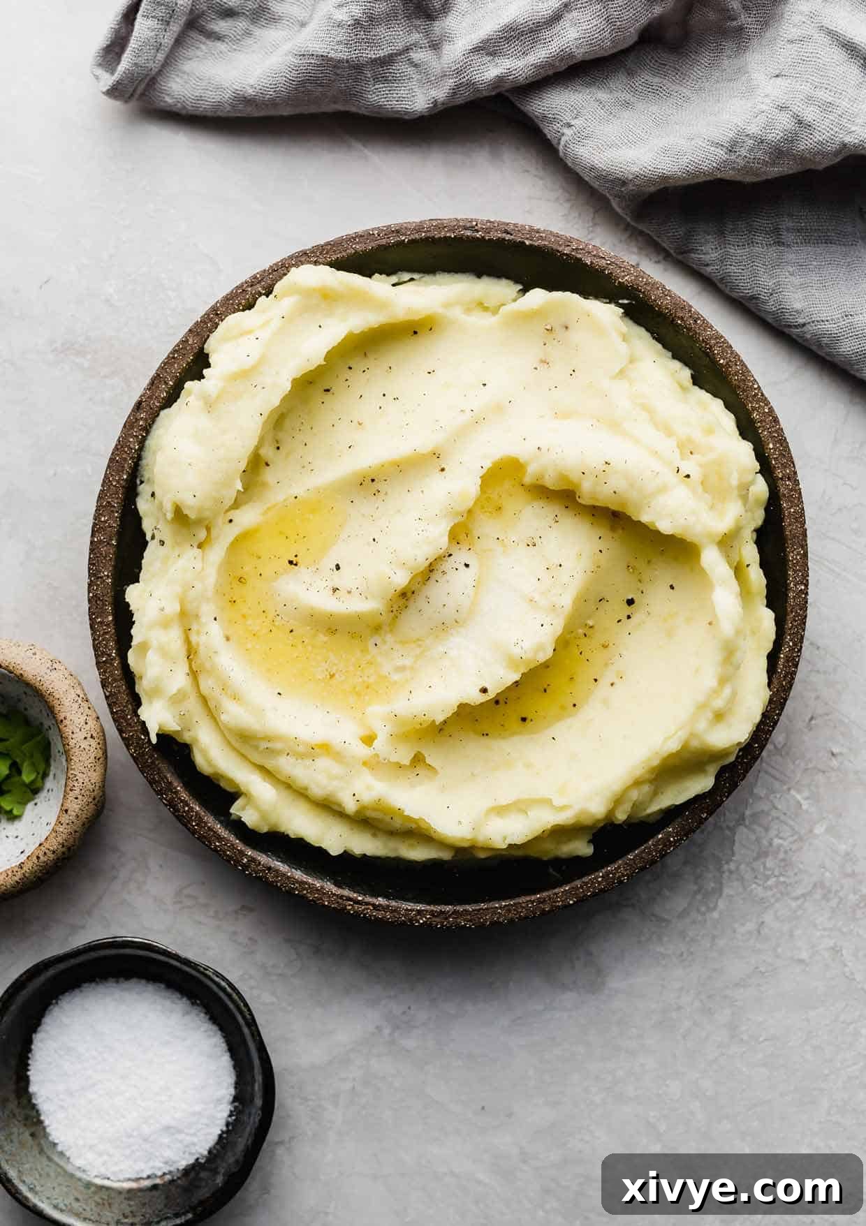 Mashed Potatoes on a black plate topped with melted butter, ready to be served.