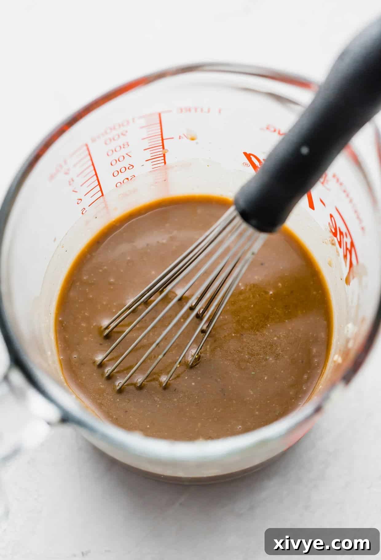 Creamy balsamic salad dressing in a glass measuring cup.