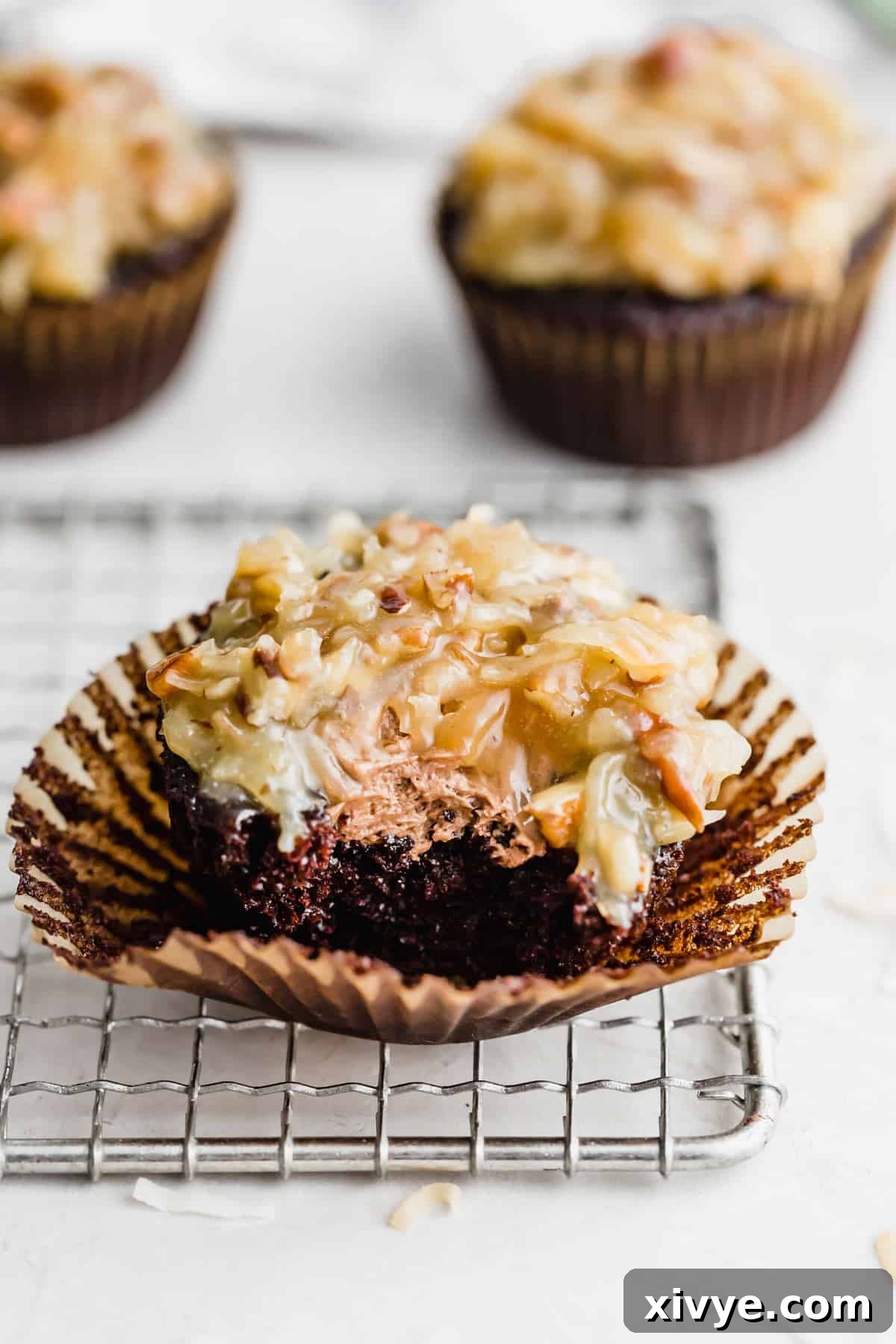 A German Chocolate Cupcake filled with chocolate frosting and topped with coconut pecan frosting, presented beautifully.