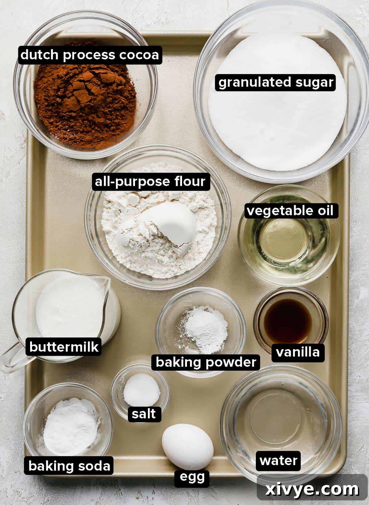 The best bakers German Chocolate Cupcakes ingredients in glass bowls on a bronze baking sheet, meticulously arranged.