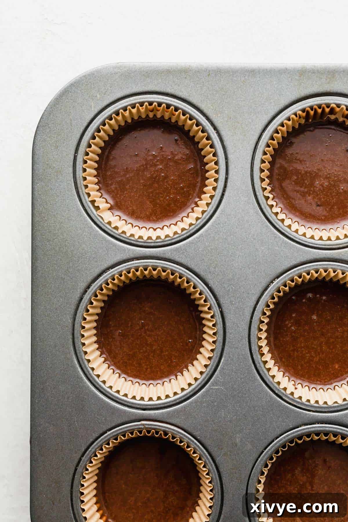 German Chocolate Cupcake batter carefully poured into tan cupcake liners, ready for baking.