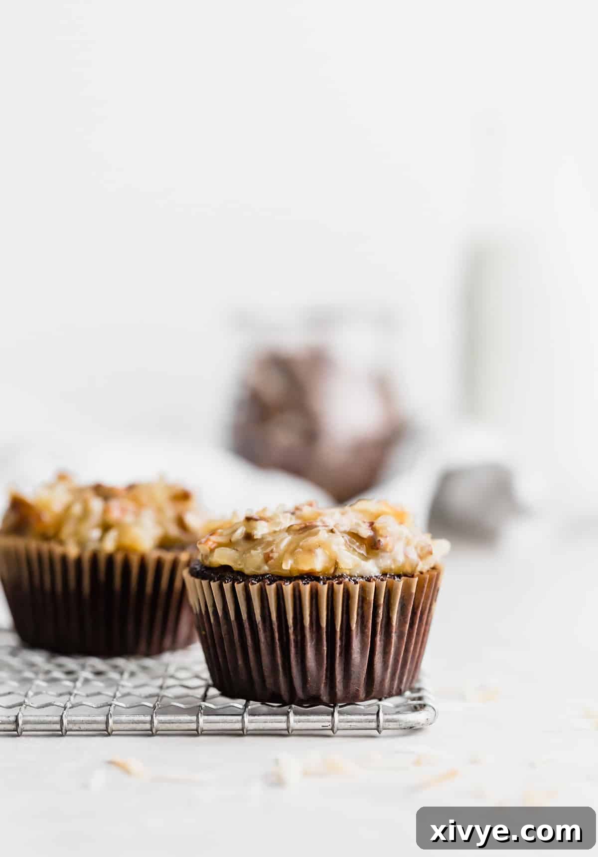 A beautifully frosted German Chocolate Cupcake against a clean white background, showcasing its rich layers.