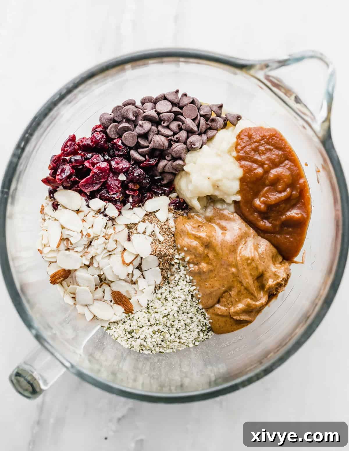 Healthy Breakfast Cookies ingredients in a glass mixing bowl: nut butter, chocolate, oats, apple sauce etc.
