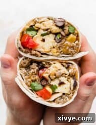 A set of hands holding a Breakfast Burrito with Black Beans that is wrapped in a tortilla and cut in half.